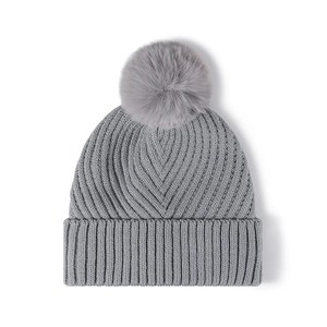 Bonnet en tricot gris d'hiver avec grand pompon en fausse fourrure et texture côtelée épaisse