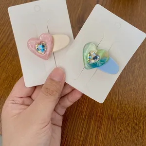Detail of candy-colored heart hair clips with marble texture and heart-shaped rhinestones