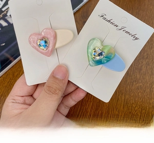 Detail of candy-colored heart hair clips with marble texture and heart-shaped rhinestones