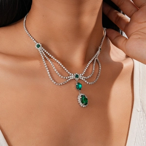 Detail of layered silver necklace with emerald pendants and crystals on model
