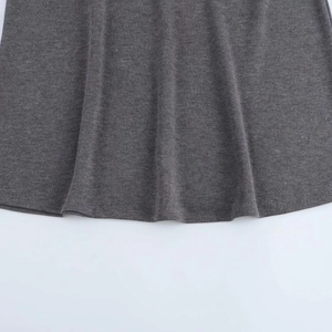 Detalle de la textura de punto gris oscuro y el dobladillo drapeado del conjunto falda
