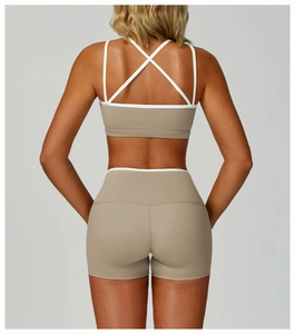 Detail of cross-back straps and khaki sports bra with white piping on a female model