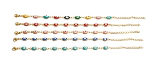 Detail of five evil eye bracelets in various colors with golden adjustable chains