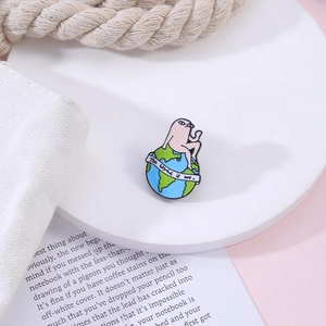 Detail of cartoon earth enamel pin with 'The world is me' banner on fabric