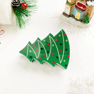 Close-up of green Christmas tree hair claw clip with colorful polka dots on festive background