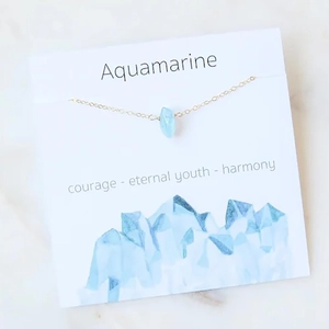 Aquamarine water drop pendant necklace with fine gold chain on minimalist marble background