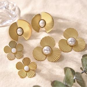 Détail de boucles d'oreilles fleurs et ginkgo dorées avec texture brossée et perles