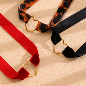 Dettagli di collane choker in velluto rosso, stampa leopardata e nastro nero con cuore oro