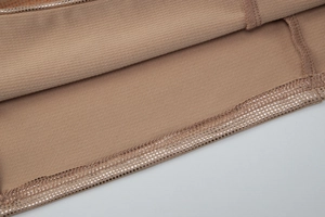 Détail macro d'un ourlet beige avec points argentés réfléchissants et coutures