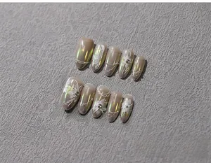 Makroaufnahme von Perlen-Nagelstickern mit weißen Blumenmotiven und Strassverzierung