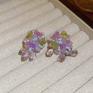 Close-up of pink and purple beaded flower earrings with teardrop crystal pendants