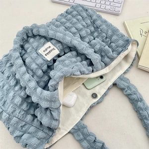 Detail of light blue bubble textured tote bag showing spacious interior and magnetic closure
