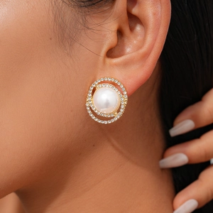 Classic gold-plated round pearl earrings with double halo diamond accents on a model