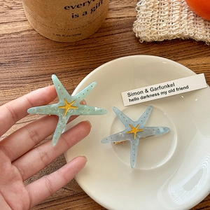 Macro detail of acrylic starfish hair clips with marble texture and golden accents