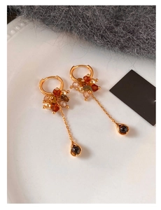 Detailed shot of golden hoop earrings with tiger eye beads and long tassel drop pendants