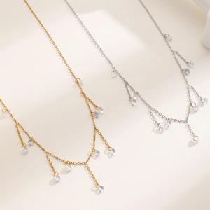 Detailed view of 18k gold and silver necklaces with dangling round cubic zirconia tassels