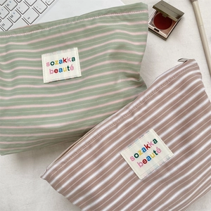 Detail of striped canvas toiletry bags with zipper closure and sozakka embroidered patch