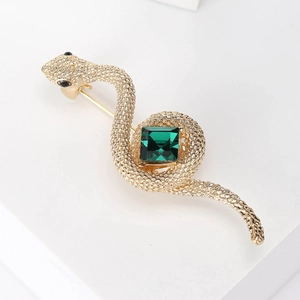 Detail of vintage snake brooch with large green gemstone and gold scale texture