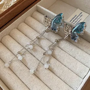 Boucles d'oreilles papillon argentées avec ailes bleues et longs pompons de perles