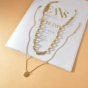 Retro double-layer gold chain necklace with square letter pendant on magazine backdrop
