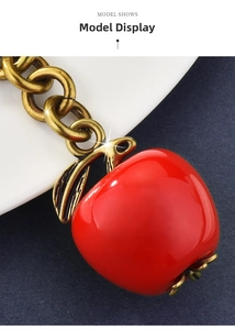 Macro shot of glossy red apple charm with vintage gold metal chain for bags