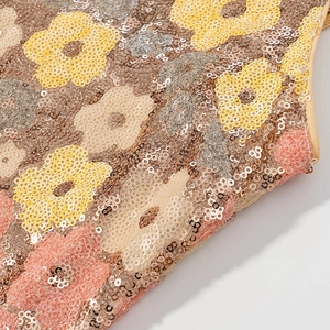 Détail macro de broderie de paillettes florales aux tons dorés et roses brillants