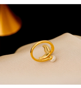Macro shot of gold mermaid tail ring with a natural freshwater pearl on beige fabric