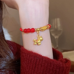 Détail d'un bracelet en perles rouges avec pendentif cheval doré sur poignet élégant