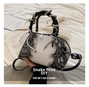 Detail showing the snake-shaped metal handle and snakeskin pattern on this crossbody bag