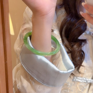 Close-up of translucent green resin geometric bangle worn on a woman's wrist