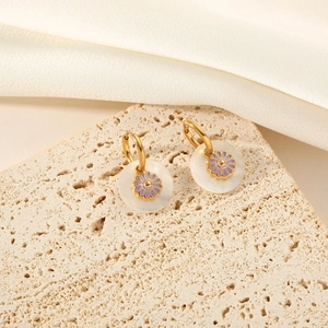 Elegant gold titanium steel shell flower earrings displayed on beige travertine stone