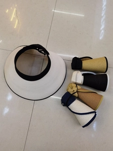 Detail of foldable straw sun visor showing rolled-up portable design in multiple colors