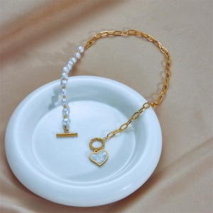 Collier asymétrique chaîne dorée et perles avec pendentif cœur sur plat céramique
