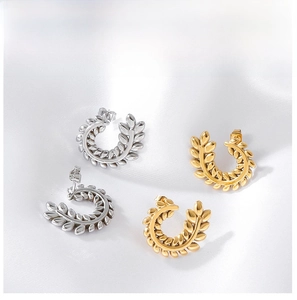 Close-up of gold and silver wheat leaf C-shaped earrings on white silk fabric
