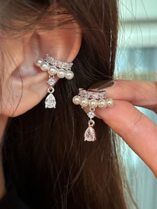 Detail of elegant pearl ear cuff with zircon drop pendant on silver plated metal