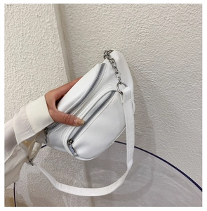 Close-up of white PU leather chest bag with silver zippers and decorative metal chain