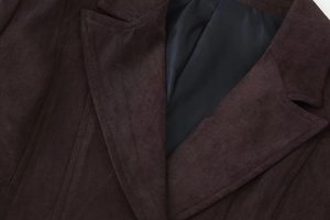 Gros plan du col à revers sur une veste en daim marron foncé montrant la texture mate fine