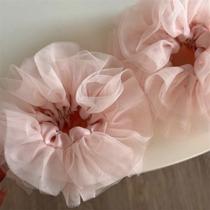 Detail of two handmade pink lace scrunchies with layered mesh and pleated texture
