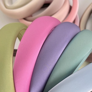 Close-up of padded satin headbands in green pink purple blue and beige pastel colors