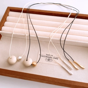 Detail of round resin pendants with metallic accents and elegant woven wax cords
