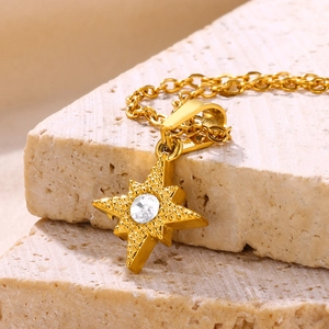 Macro shot of 18K gold star pendant with zircon on textured stone background