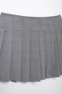 Gros plan sur la jupe plissée à carreaux gris avec boucle et texture de tissu