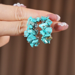 Vue macro de boucles d'oreilles argentées en C avec pierres turquoises et détails ciselés