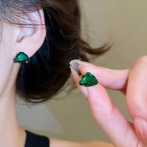 Detail shot of faceted emerald green triangular stud earrings with silver posts.