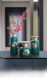 Detail shot of green ceramic vases with gold ginkgo leaves on a marble console table