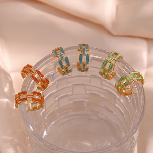 Close-up of colorful enamel hollow chain earrings hanging on a clear glass edge