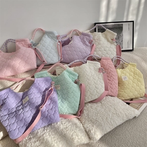 Détails de la texture matelassée en cœur et couleurs macaron pour ce sac en toile