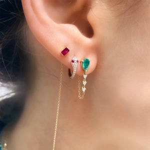 Macro shot of S925 silver earrings with emerald, ruby stones and diamond snake chain details