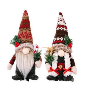 Christmas gnome dolls with knitted hats holding candy cane and ski poles on white background
