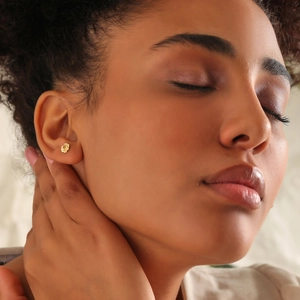 Close-up of elegant gold flower earrings worn by a model in a minimalist style